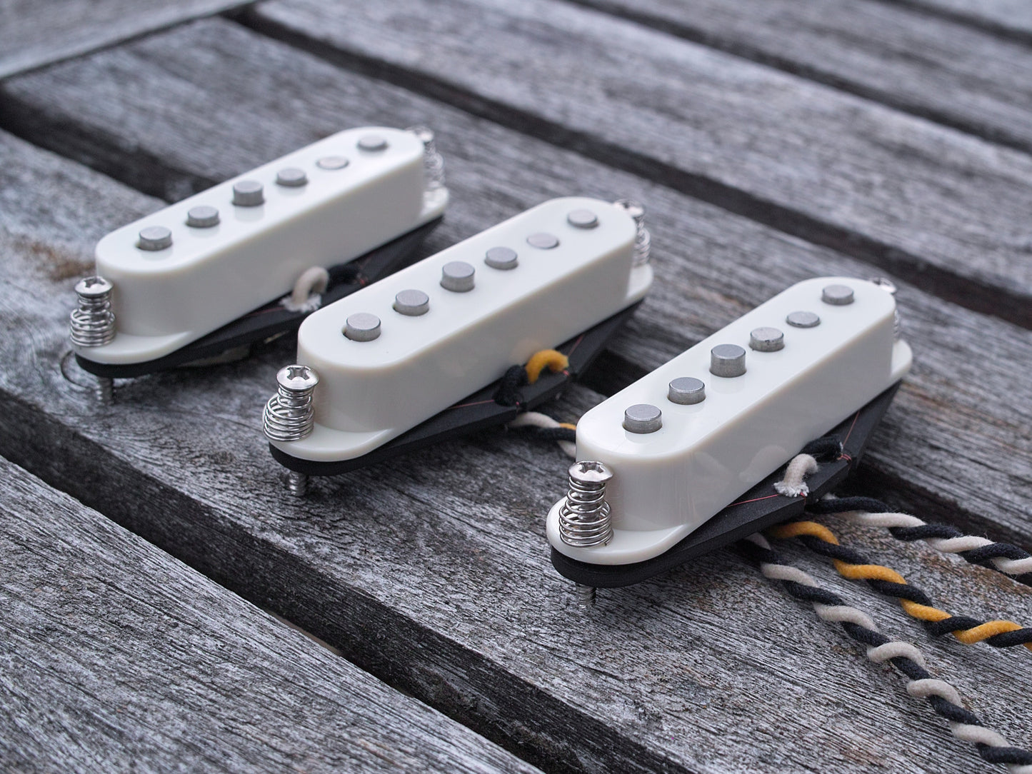 Three pickups for Stratocaster style electric guitars with staggered poles and parchment covers.