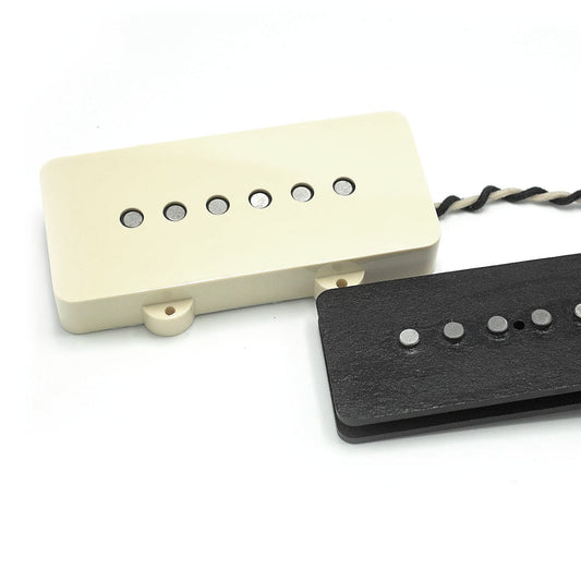 Two Lake Surfer model pickups for Jazzmaster-style guitars on a white background. One has a parchment cover on and the other does not have a cover on.