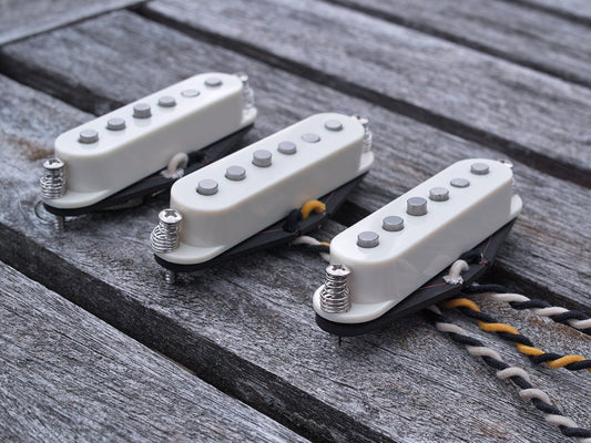 Three pickups for Stratocaster style electric guitars with staggered poles and parchment covers. 
